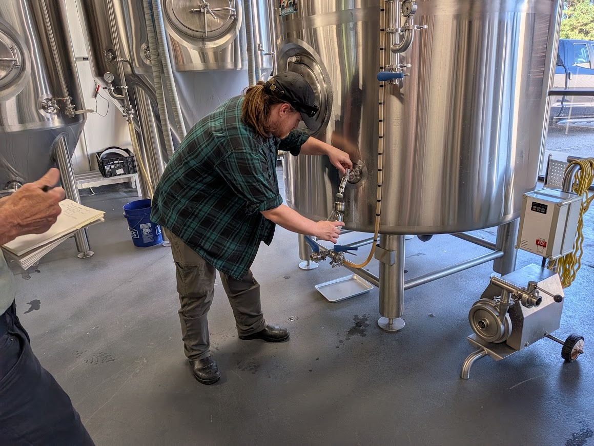 brewer pulling from a tap at compass rose brewing