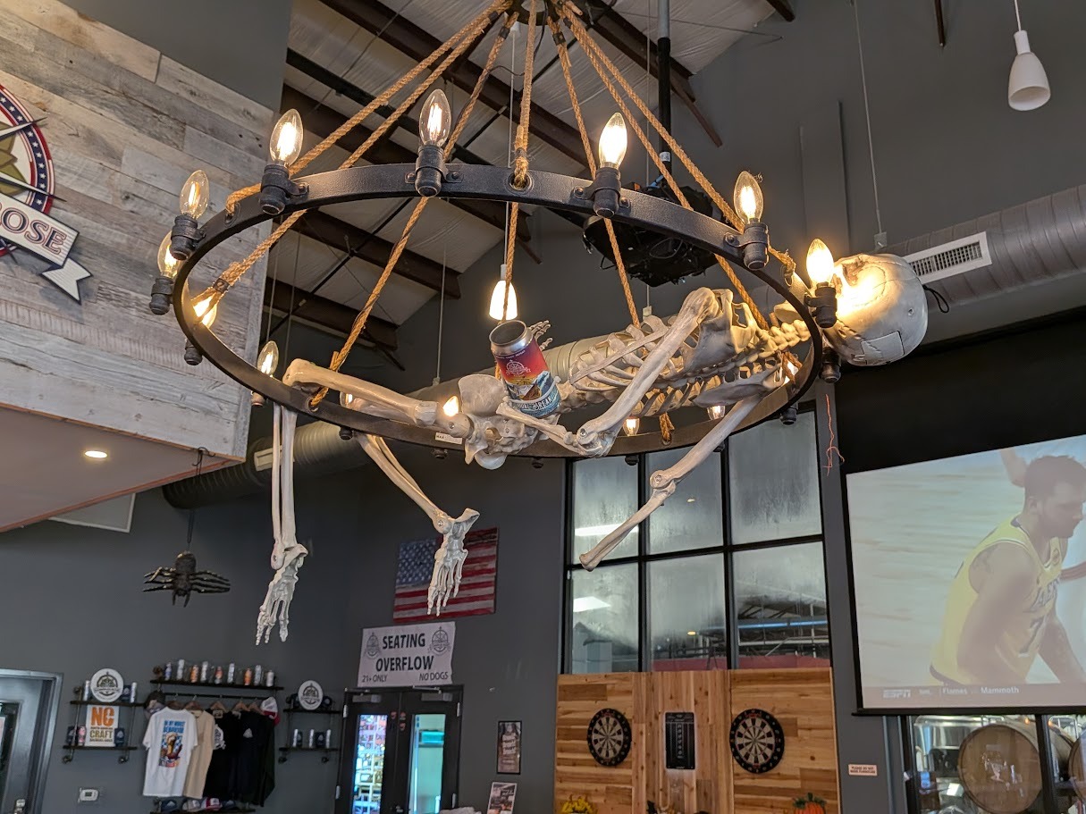skeleton hanging from a wheel-shaped chandelier