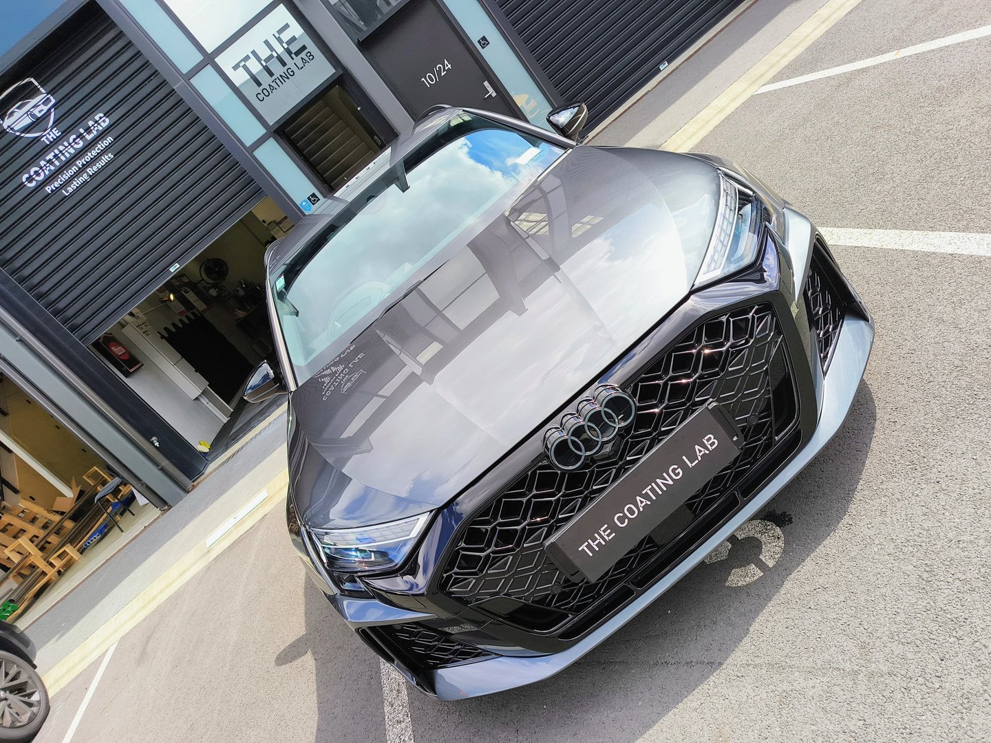 A glossy grey Audi RS3 with ceramic coating parked outside The Coating Lab detailing shop.