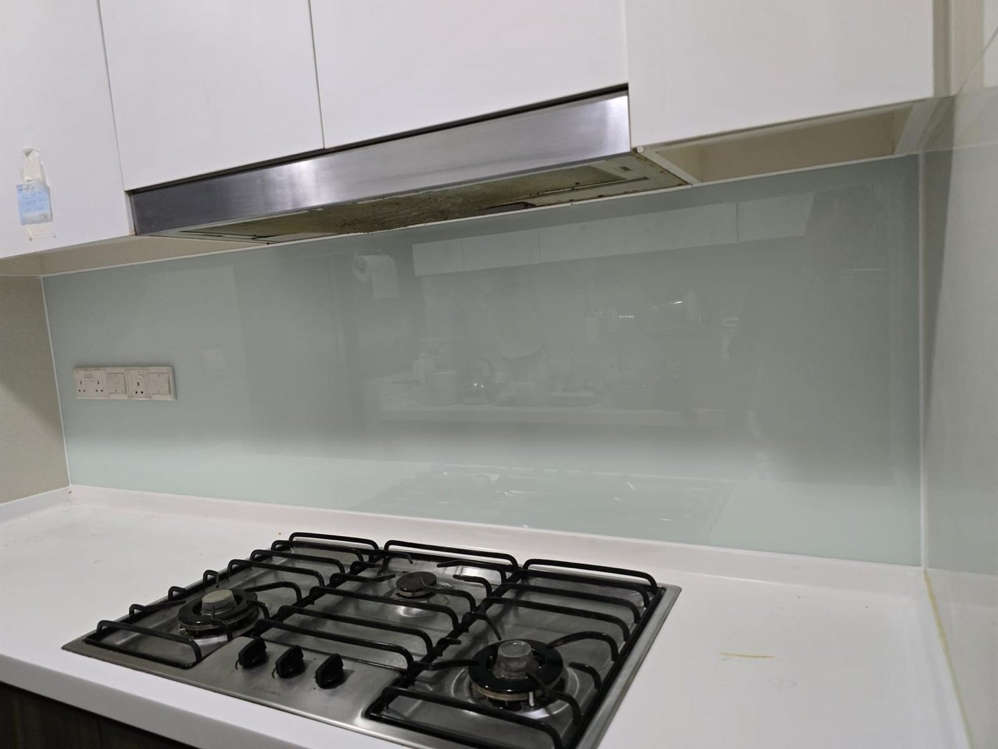Modern kitchen featuring a sleek glass backsplash behind a stainless steel gas stove and range hood.