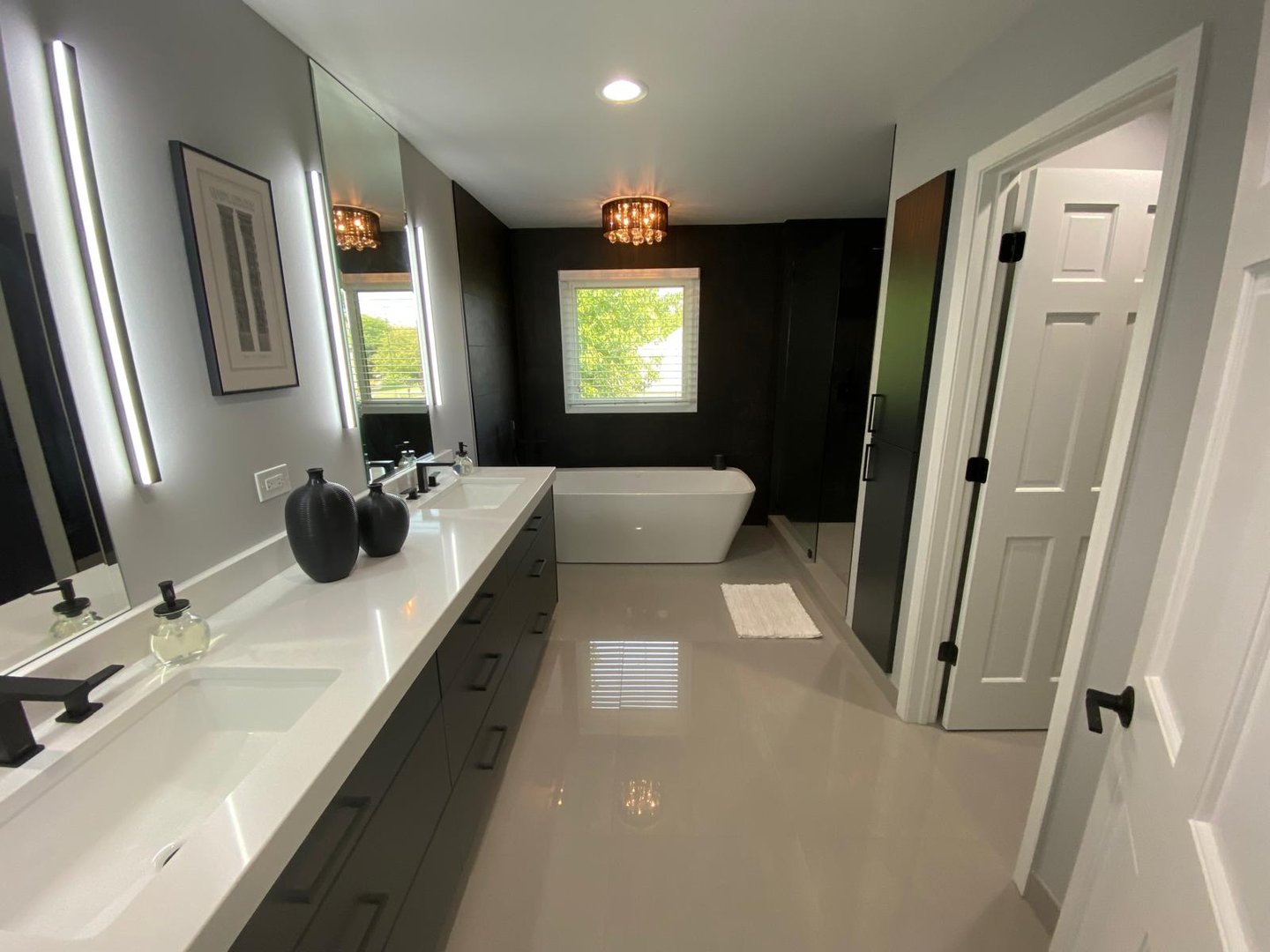 Modern luxury bathroom with double vanity, white quartz countertops, and a freestanding soaking tub.
