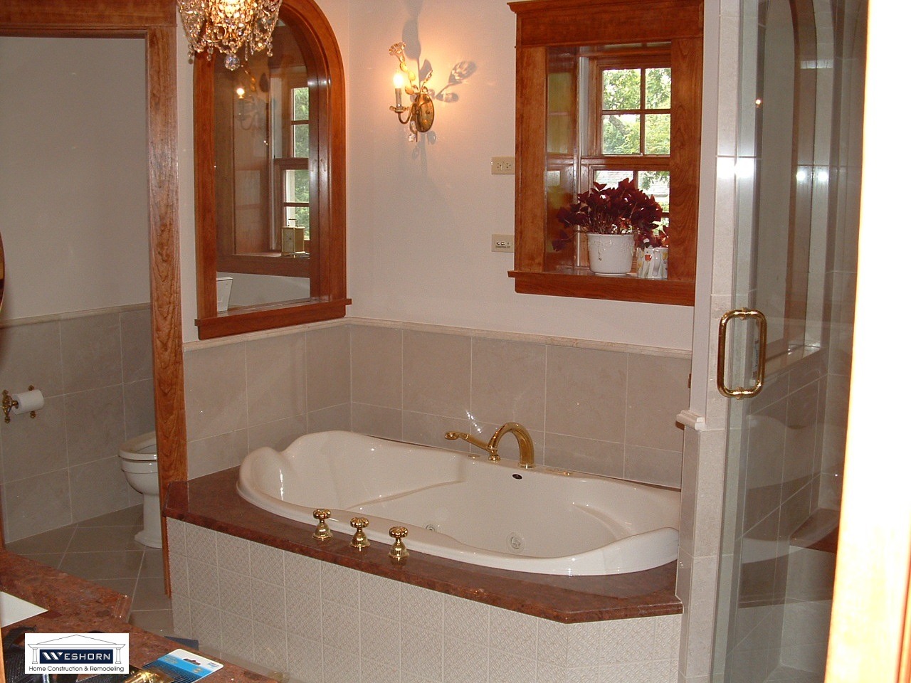 Luxury master bathroom featuring a built-in jetted soaking tub with gold fixtures and elegant wood trim.