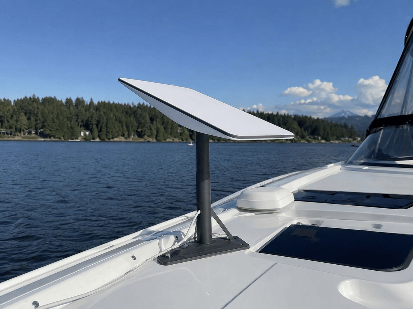 A Starlink satellite internet dish mounted on a white boat deck with a scenic lake background.