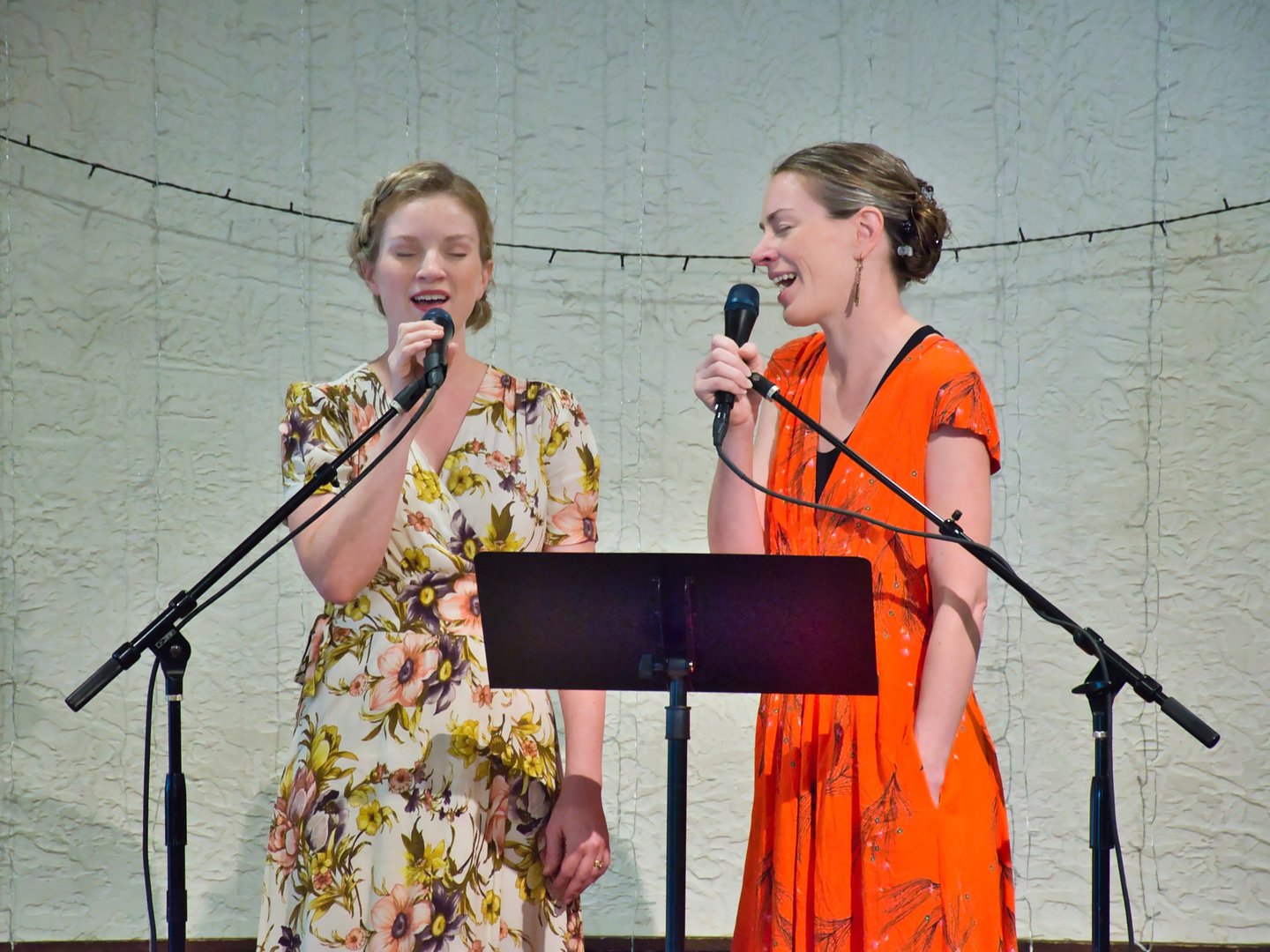 two women singing in front of microphones