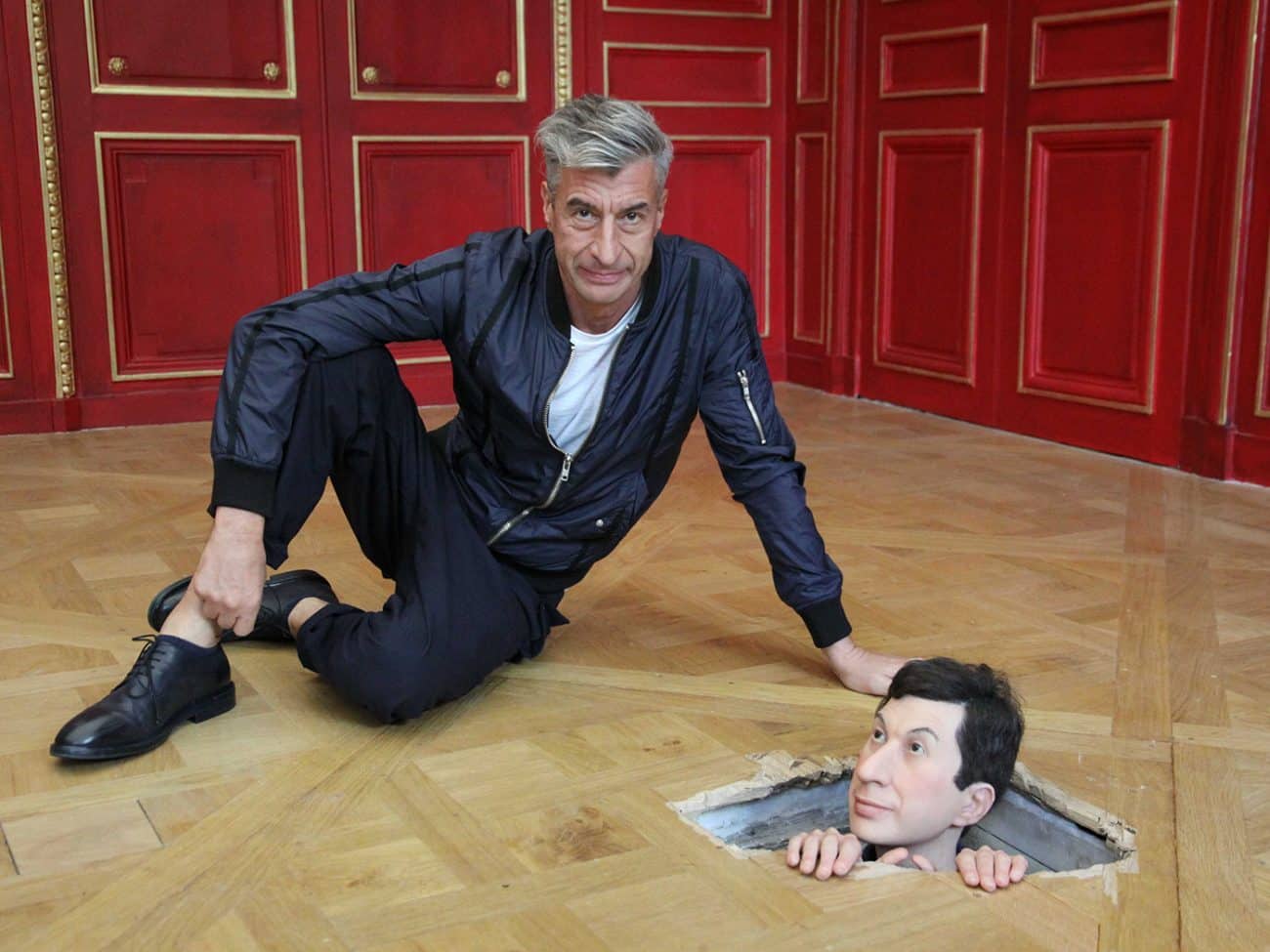 Maurizio Cattelan posando à beira de “Little Cattelan from Rotterdam” (2010) durante a exposição
