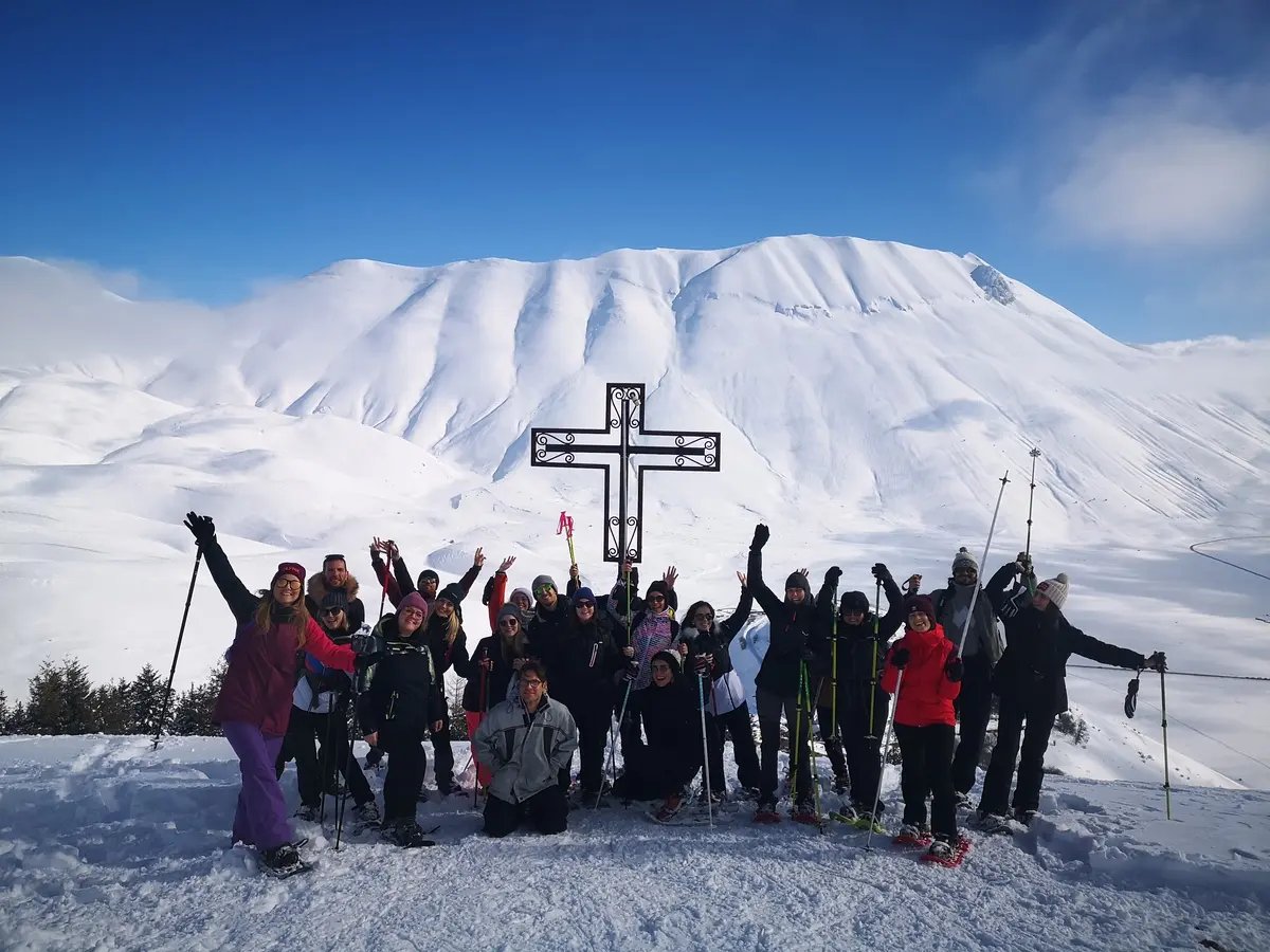 Foto di gruppo tra la neve in ciaspole alla croce del Monte Veletta sopra Castelluccio di Norcia