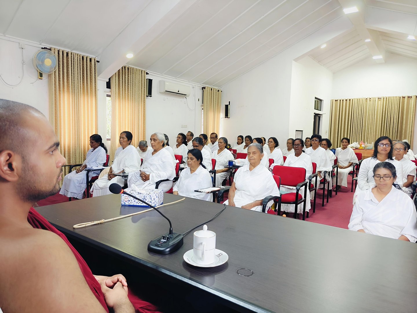 a man in a red robe is speaking to a group of people