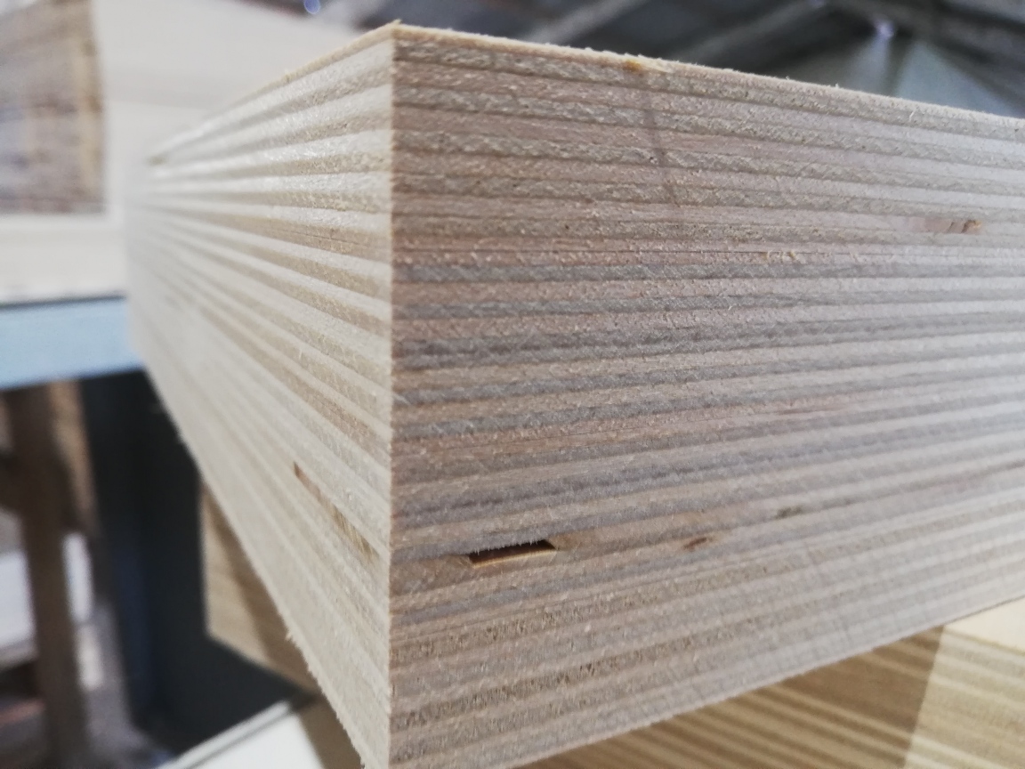 Close-up of stacked birch plywood sheets showing the layered wood grain edges for construction.
