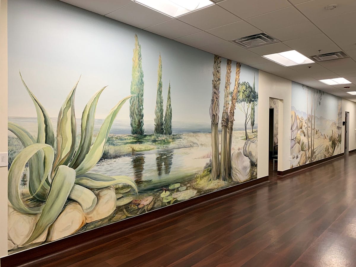 Two large panoramic murals in a clinic hallway depicting Southern Californian landscapes.