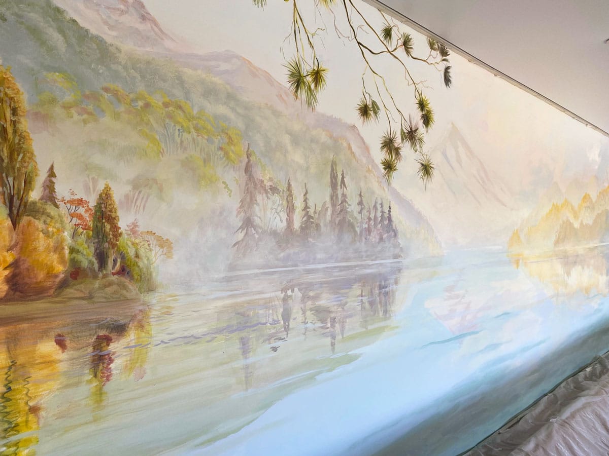 Angled view of pool mural showing New Zealand lake, misty mountains and trees.