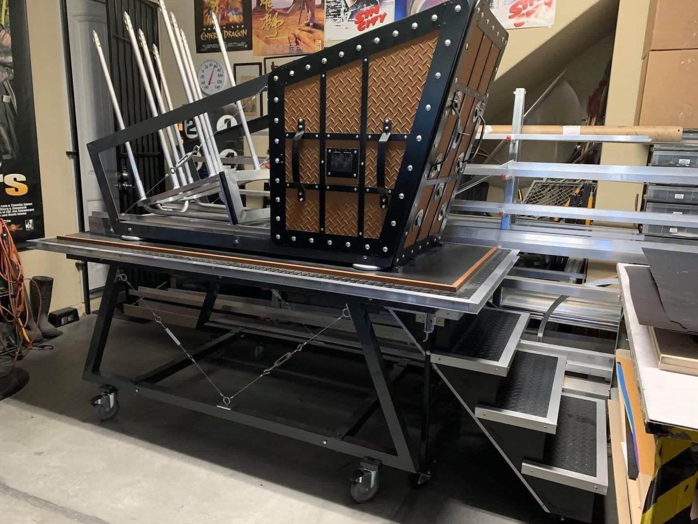Fire spiker illusion prop featuring a black metal frame and spiked trap door on a rolling table.