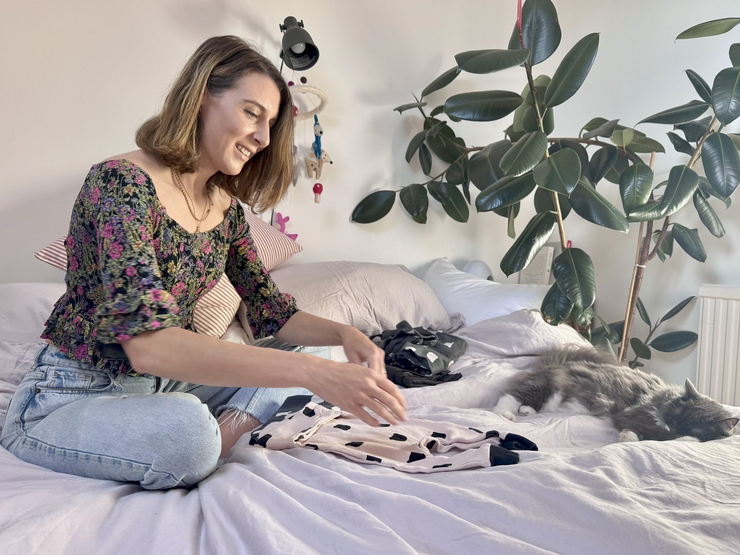 woman sitting on a bed folding clothes
