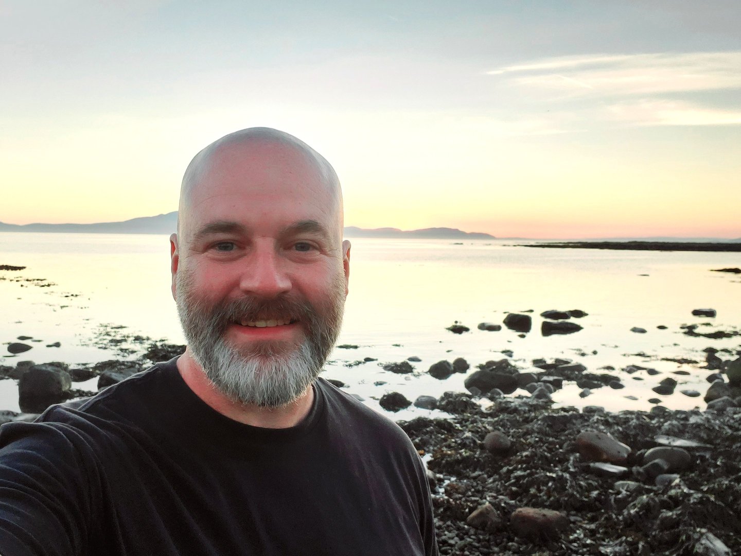 Photo of Life First Then Work founder Andy standing by the sea at sunset