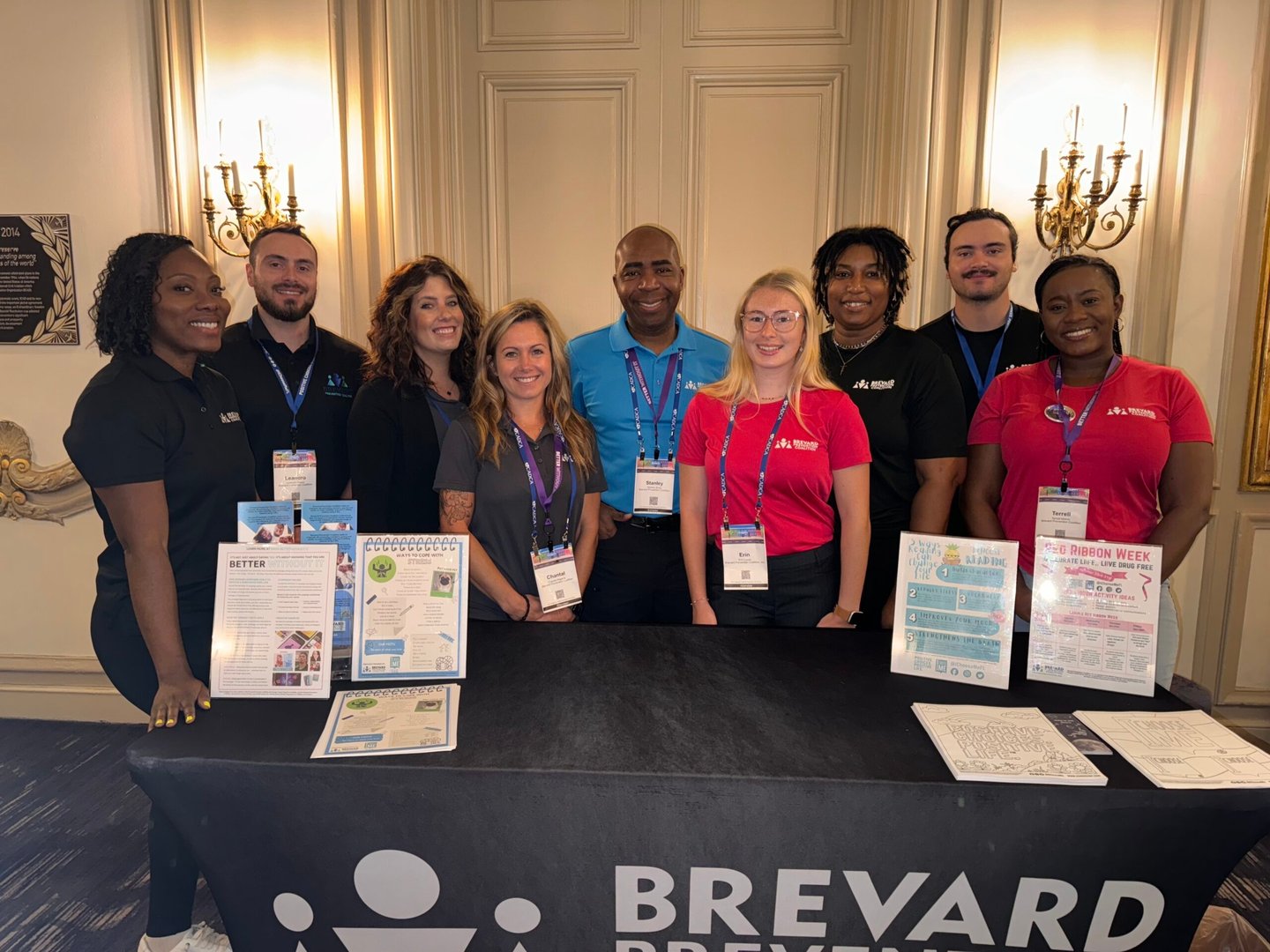 a group of people standing around an information booth smiling