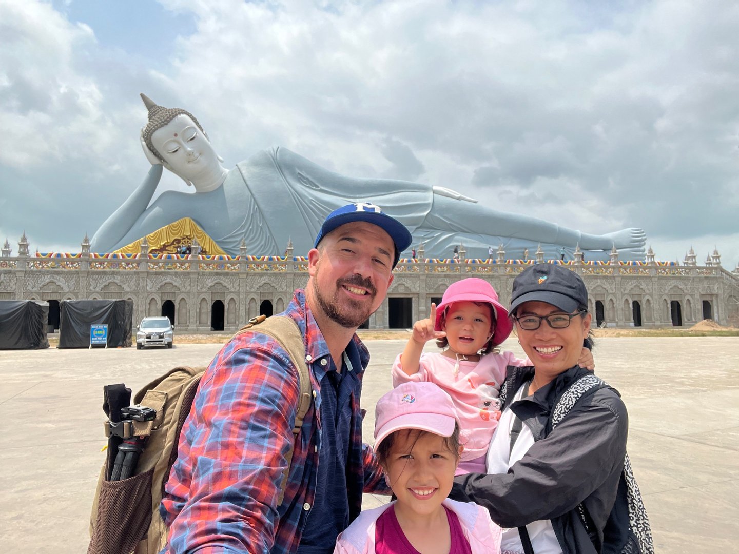 a family posing for a photo in front of a large statue of a buddha statue