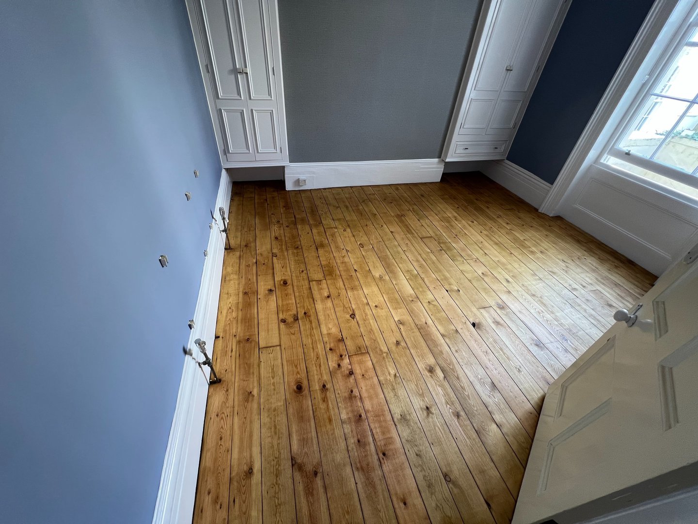 Brighton office featuring restored pine wood flooring, blue walls, and built-in white wardrobes.