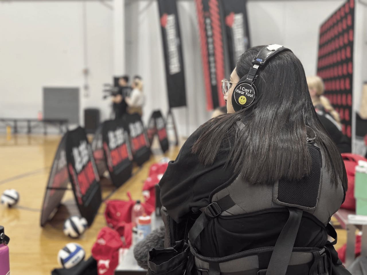 a woman in a black jacket and headphones on a basketball court