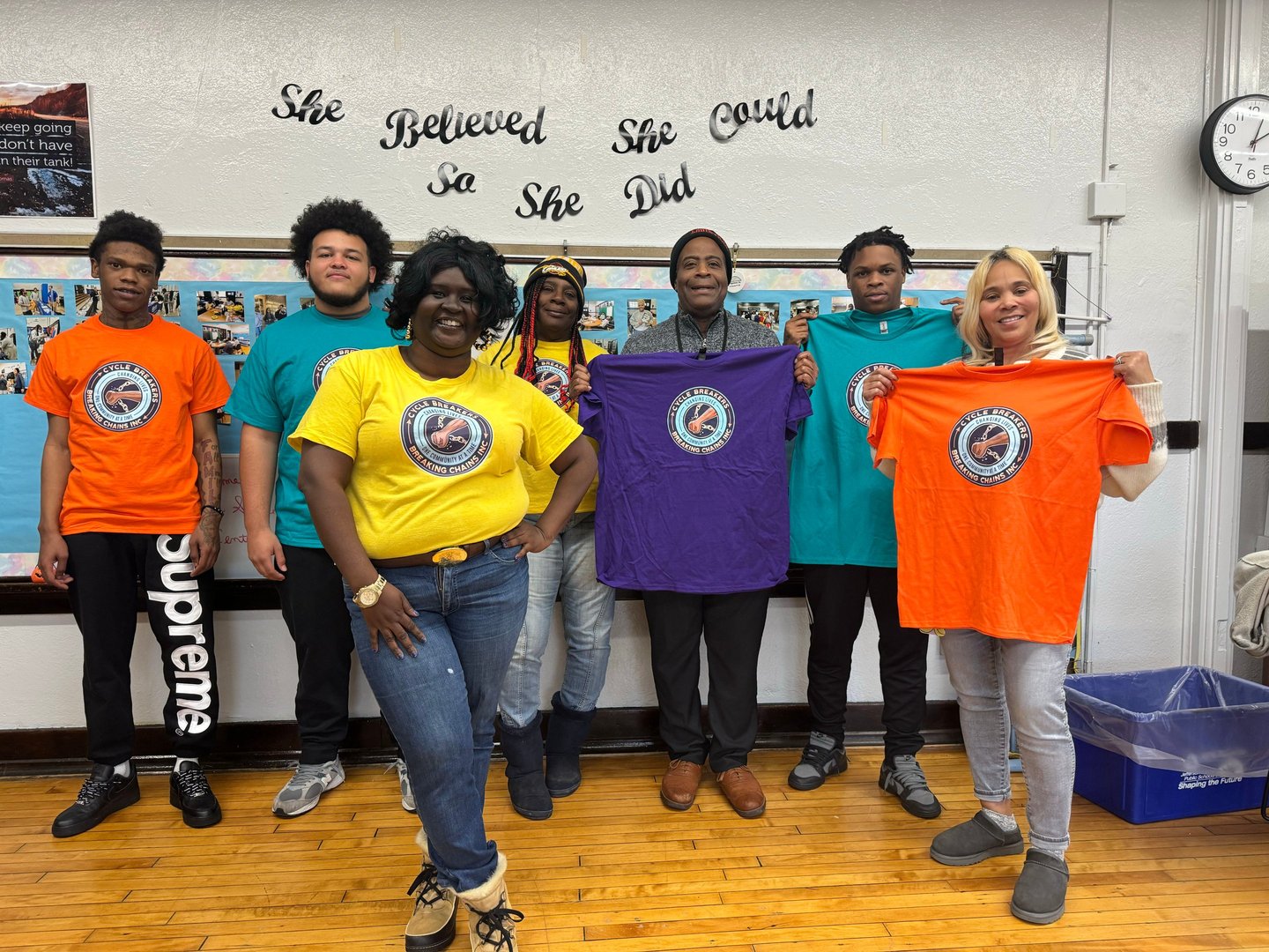 A group of diverse community members proudly holding up Cycle Breakers Breaking Chains T-shirts.