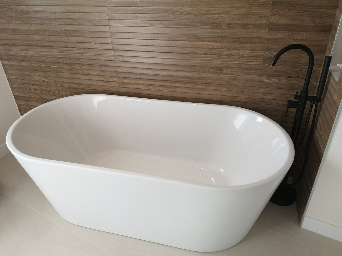 Baignoire ilot, faïence imitation bois, robinetterie noire.