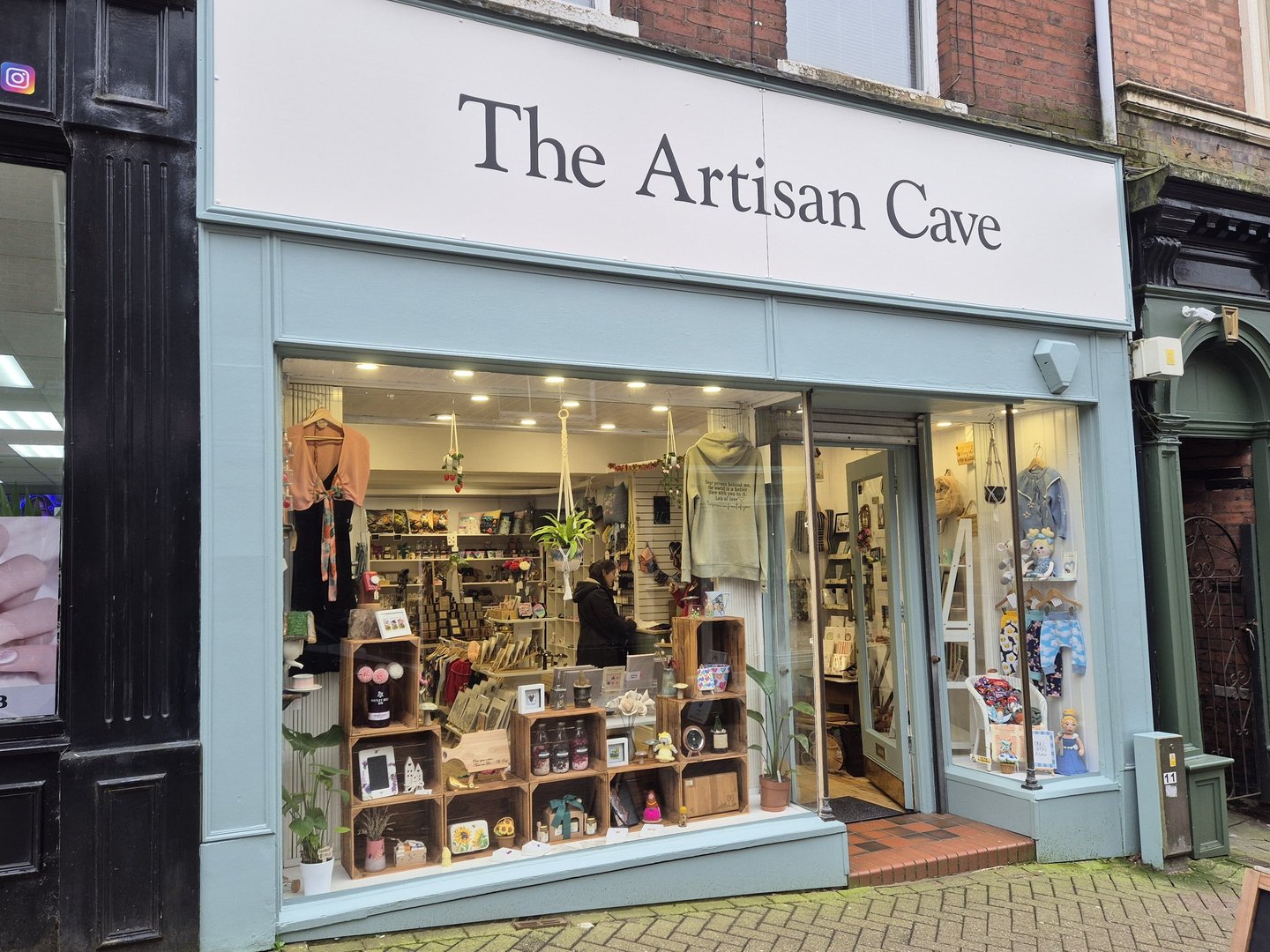 The Artisan Cave storefront featuring handmade gifts and local crafts in a boutique window display.