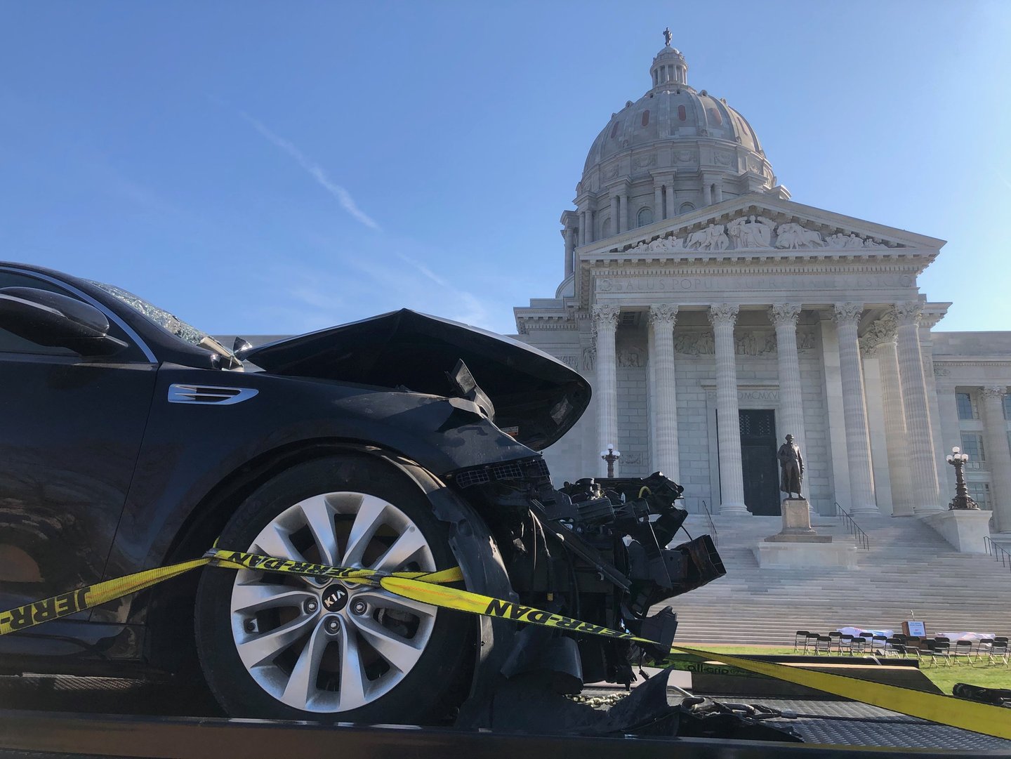 The front of a car that has been in a wreck, with the Missouri capital building in the background