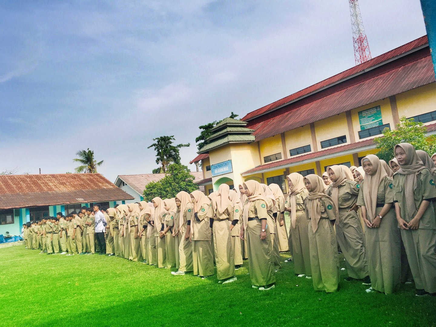 a group of people standing in line in front of a building SMK ASY-SYIFA Bekasi