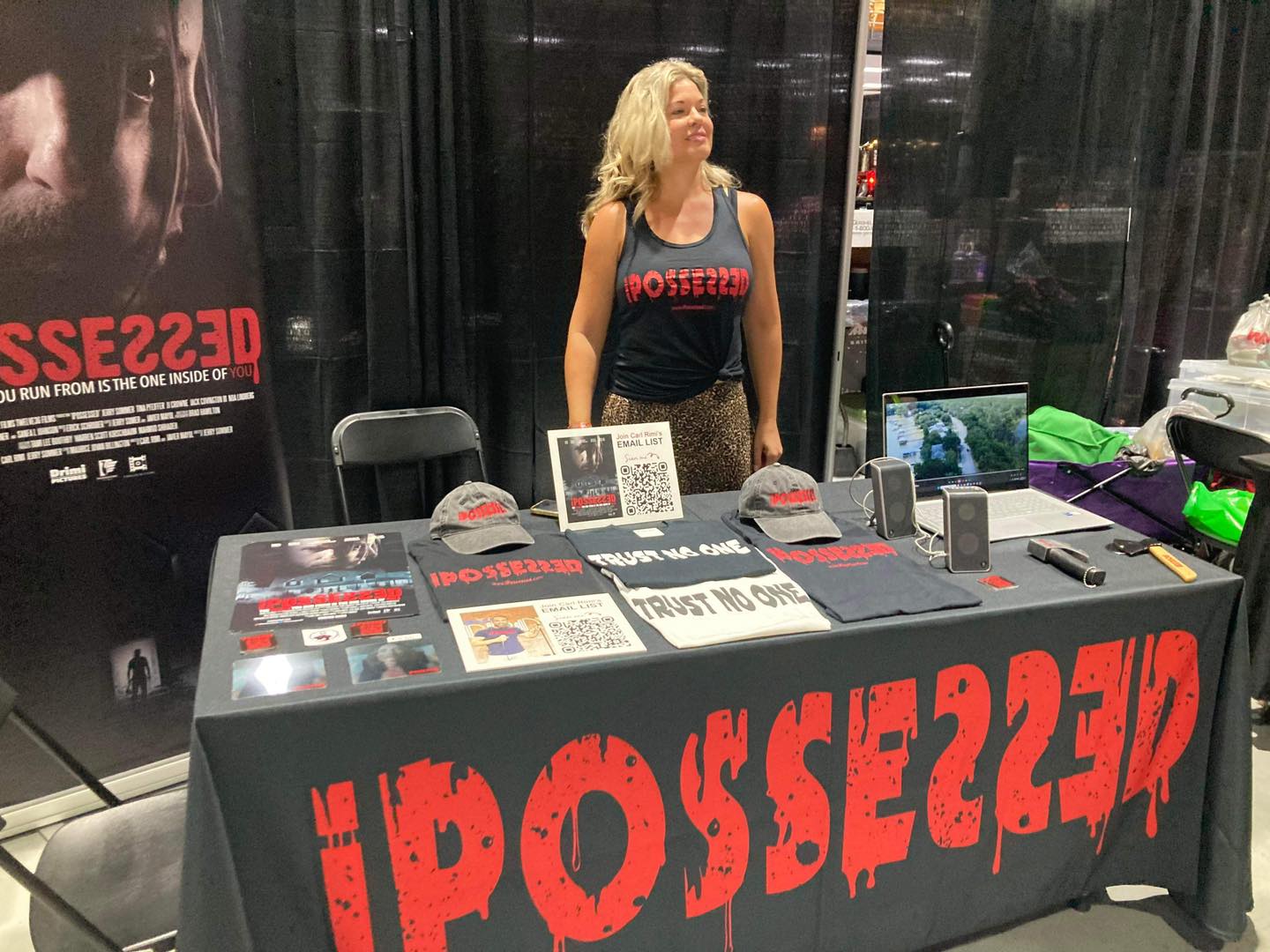 a woman standing in front of a table with a sign that says possy