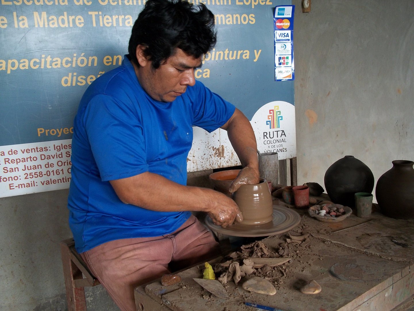 Artisan craftsman shapes a clay pot on a traditional pottery wheel in an art workshop.
