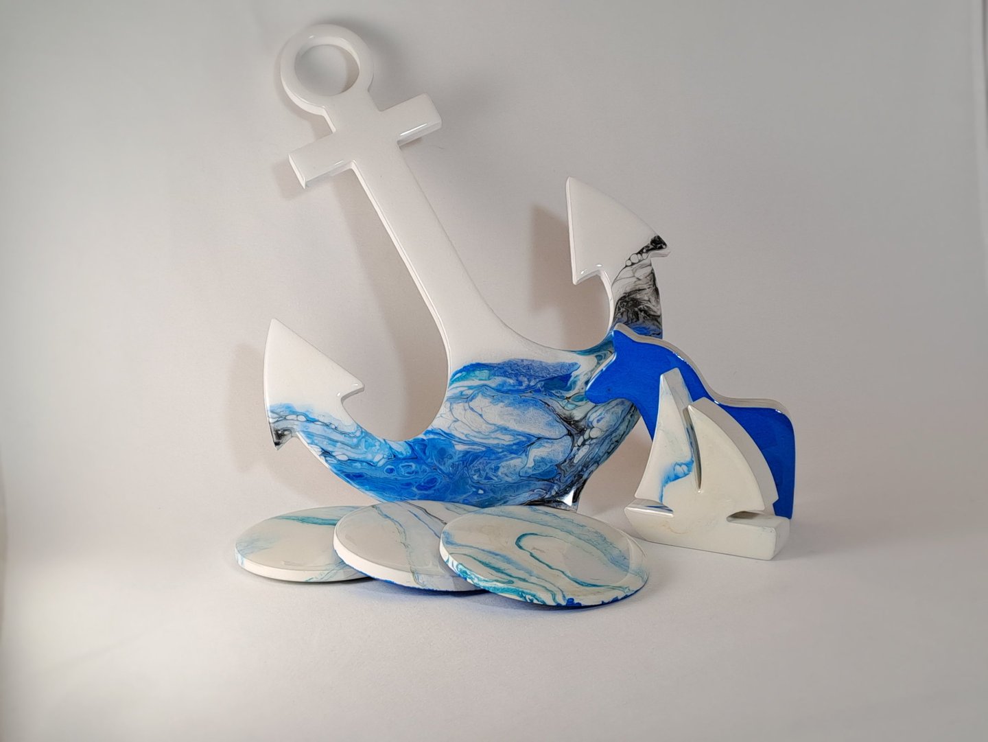 Nautical resin art set featuring a blue and white anchor, sailboat decor, and marbled coasters.