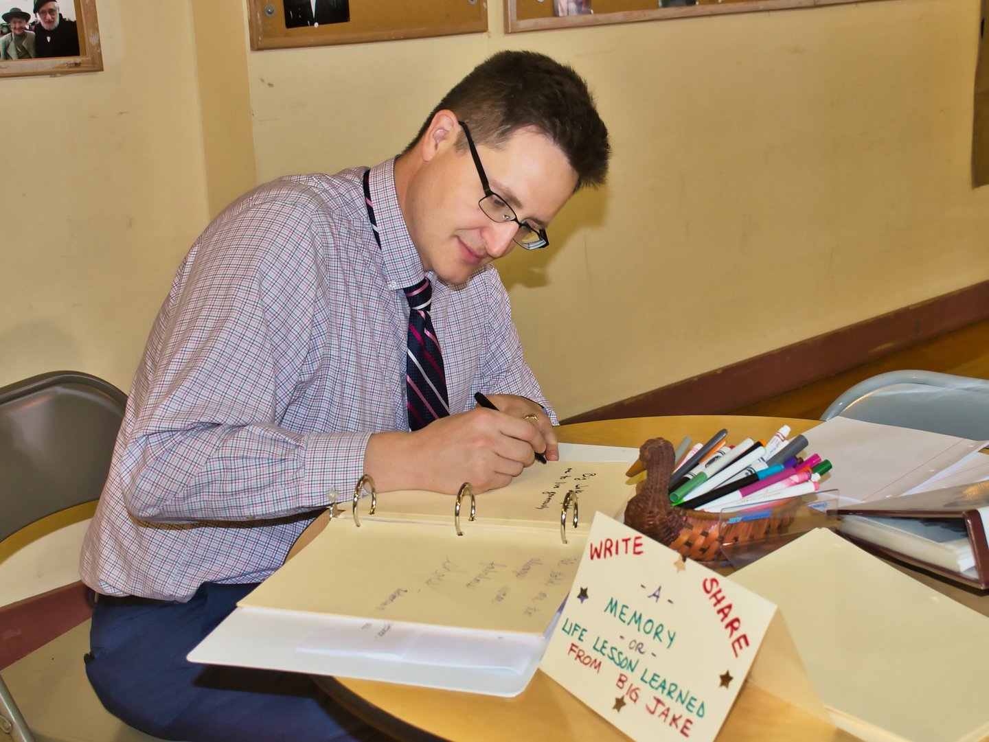 a man sitting at a table writing on a notepad
