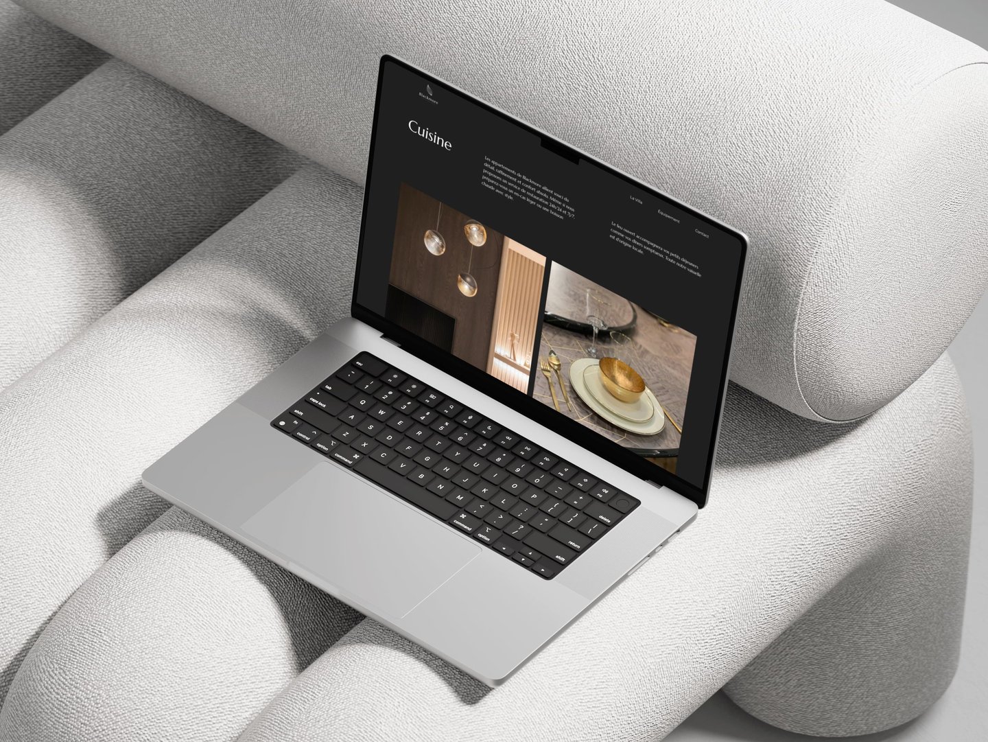 A silver laptop displaying a modern web design layout on a textured grey sofa.