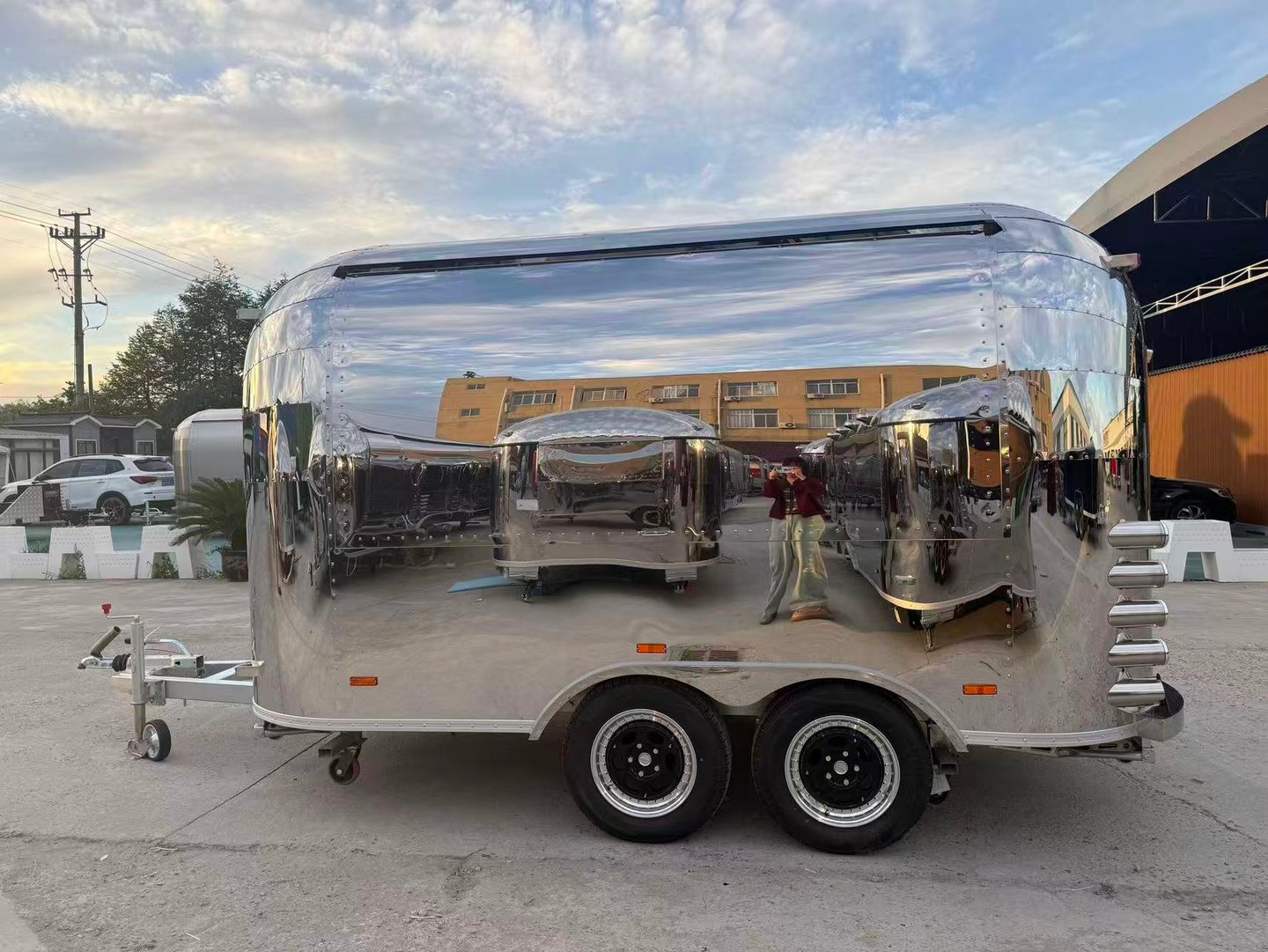 Polished chrome airstream food trailer parked outdoors with a highly reflective mirror finish.