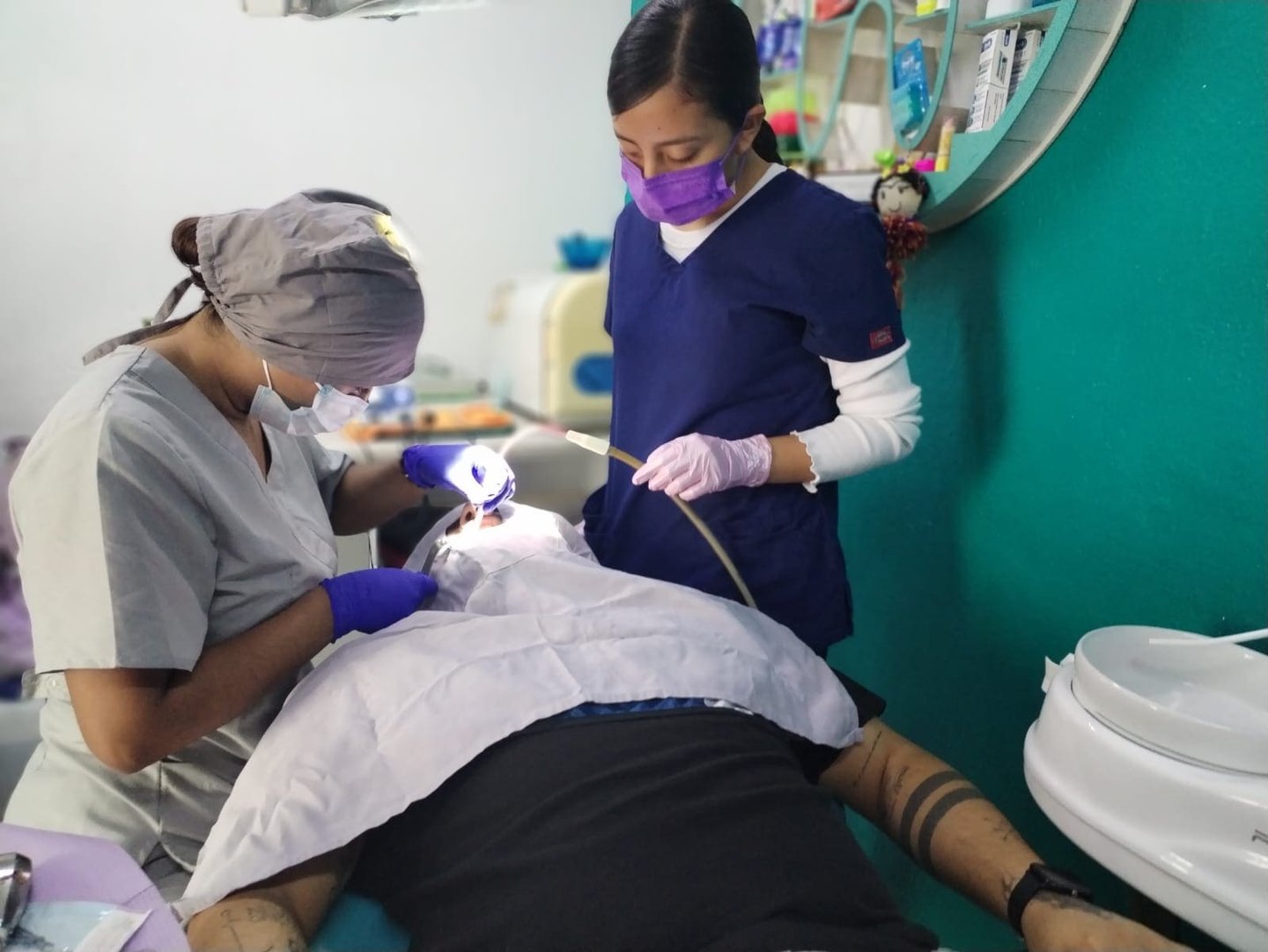 Dentista profesional y asistente realizando un procedimiento dental a un paciente en clínica
