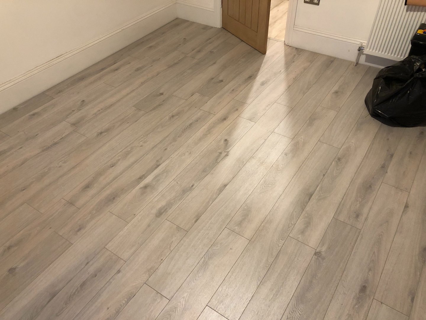 Modern grey oak laminate flooring installed in a Hove residential room with white skirting boards.