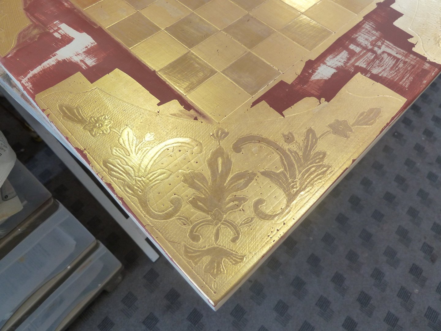 Détail de la pose de dorure à la feuille d'or pour le décor d'un échiquier.