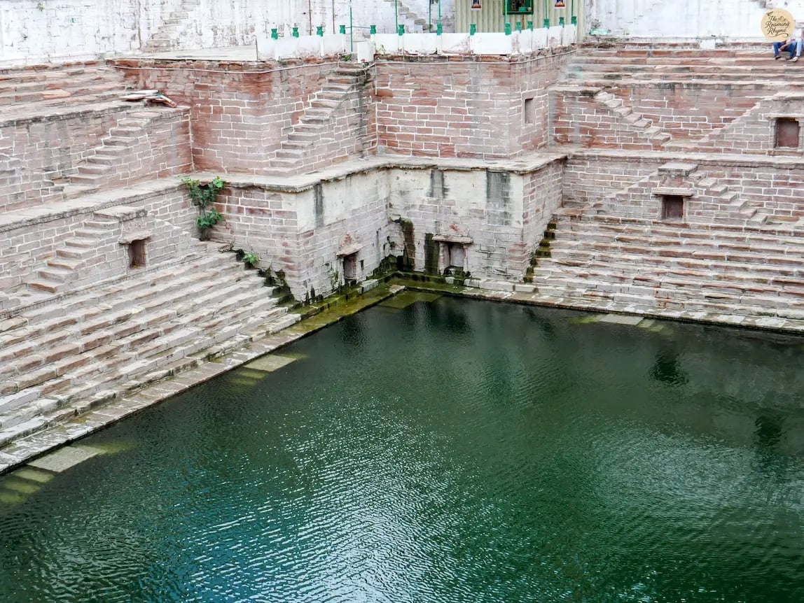 Beautiful stepwell Toorji ka Jhalra in Jodhpur with stone carvings and reflective waters.