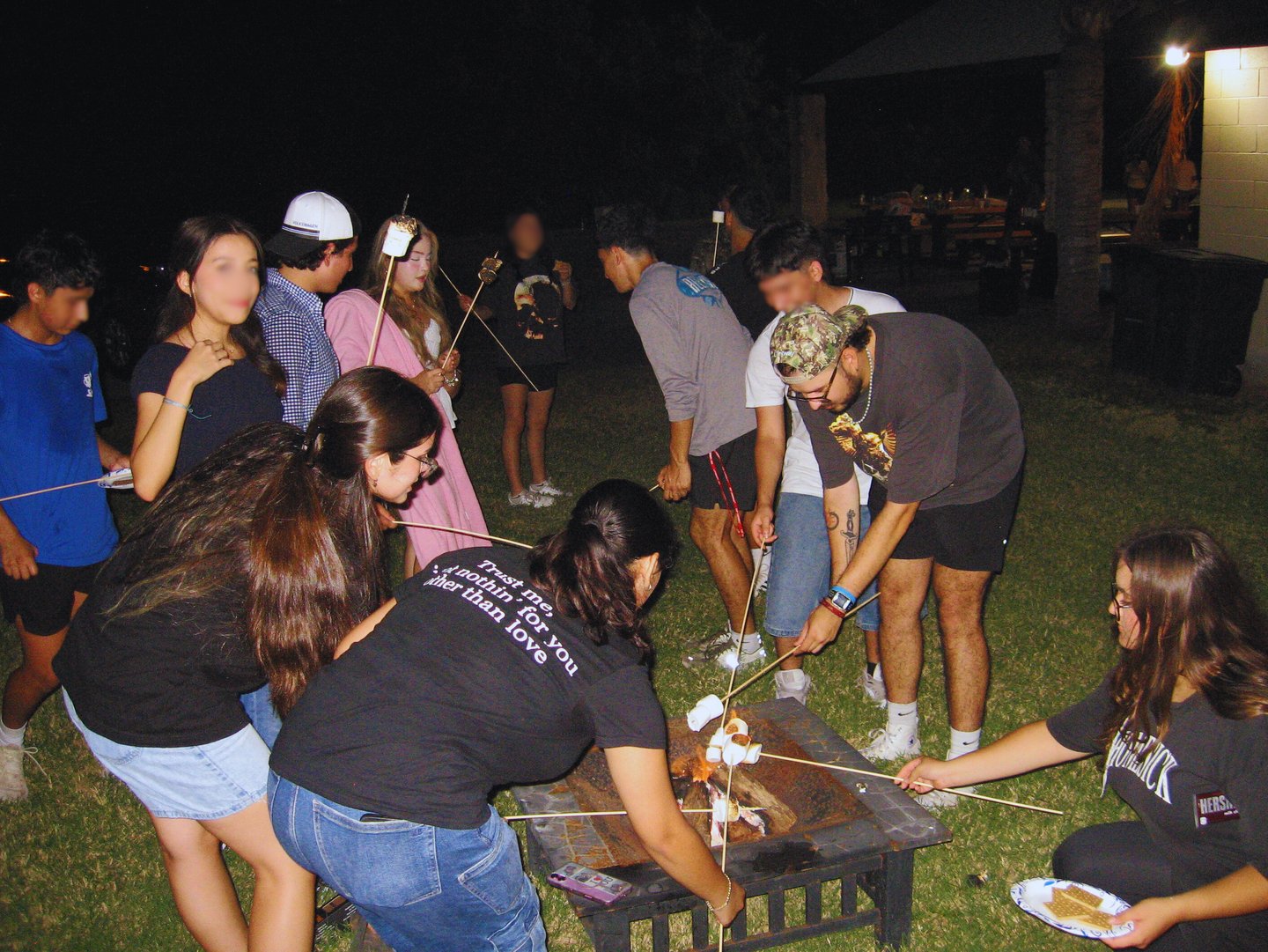With young people roasting marshmallows outside by a campfire.