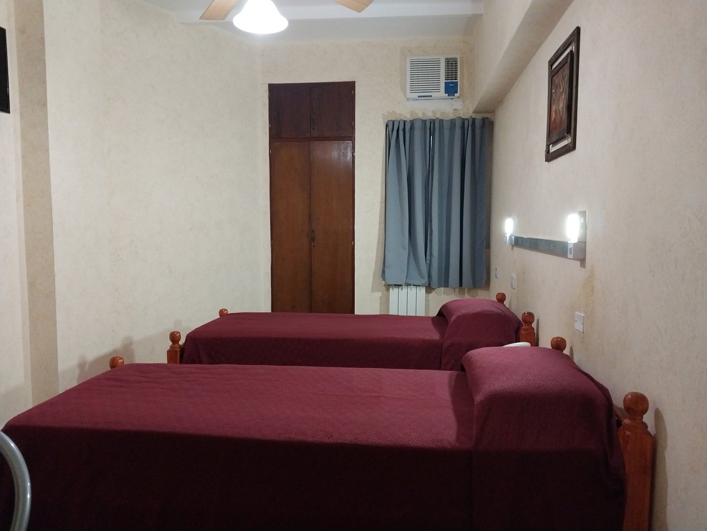 Una habitación con 2 camas y un ventilador.