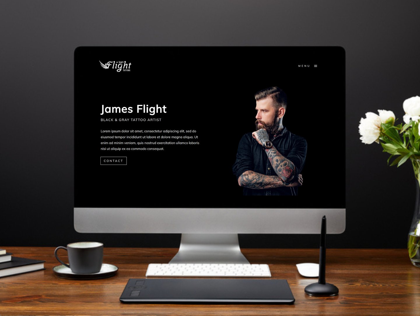 a computer screen on a desk featuring the homepage of a tattoo artist website