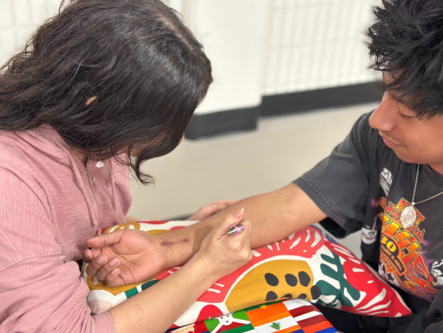 young woman applying henna to forearm of smiling young man