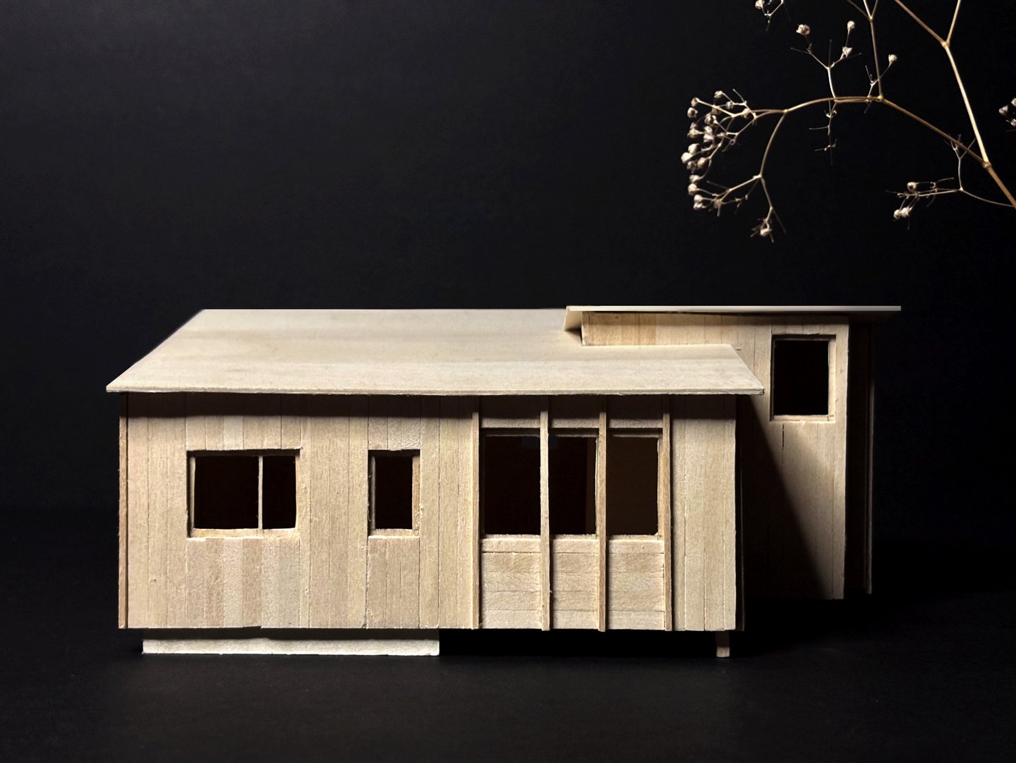 Handcrafted basswood architectural model of a modern cabin design against a dark background.