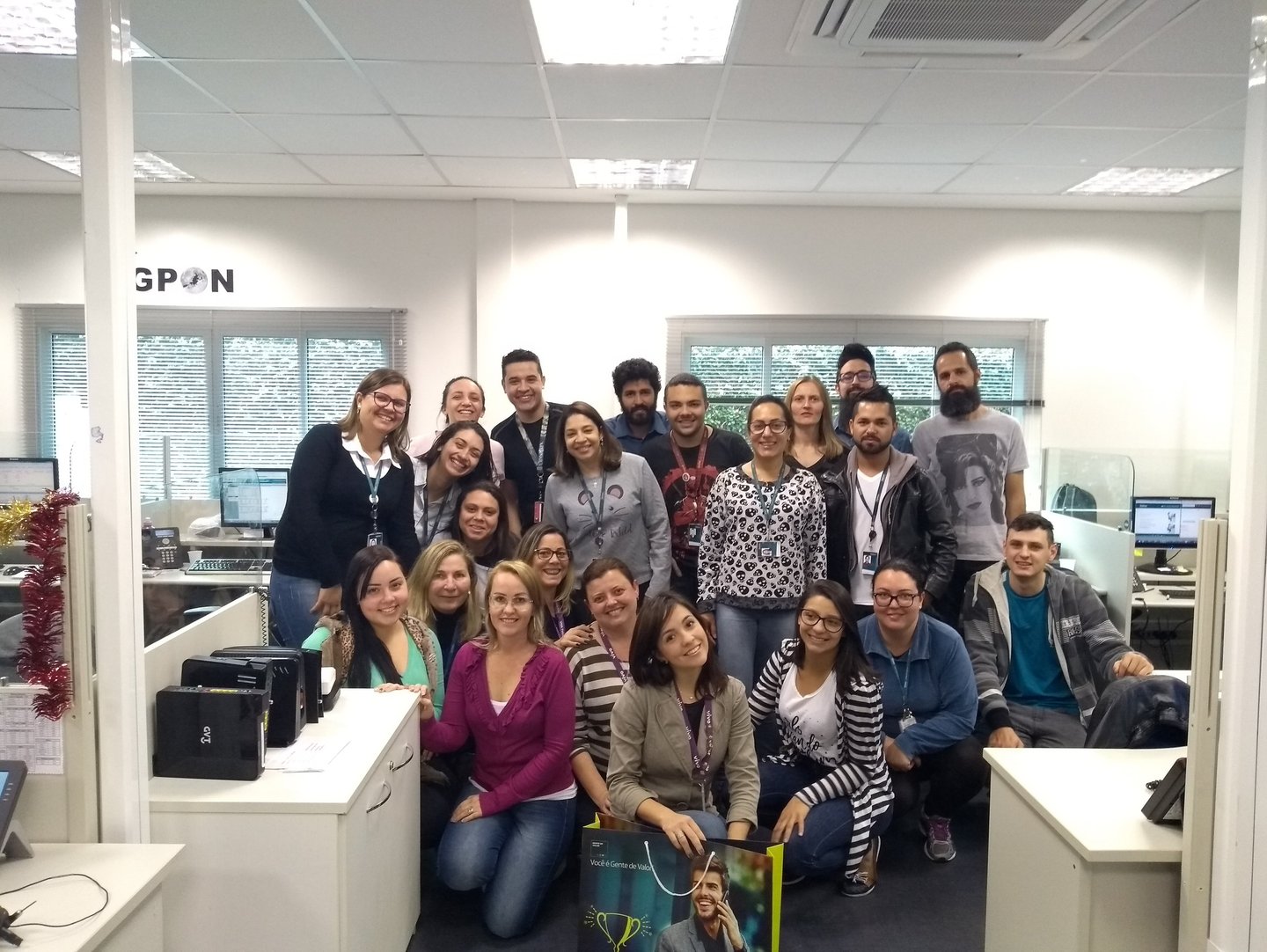 uma equipe de trabalho, um grupo de pessoas em pé ao redor de uma mesa posando para uma foto