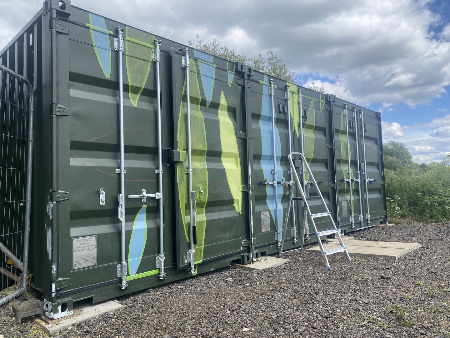 Three-quarter view of shipping container with painted colours filling taped leaf shapes