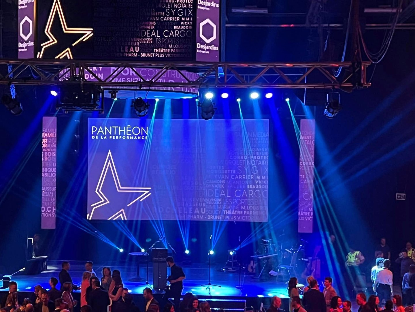 Pantheon de la Performance gala stage with blue spotlight beams and corporate sponsor logos.