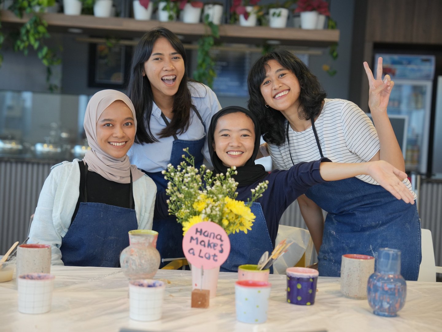 a group of women posing behind a table with flowers and handmade pots
