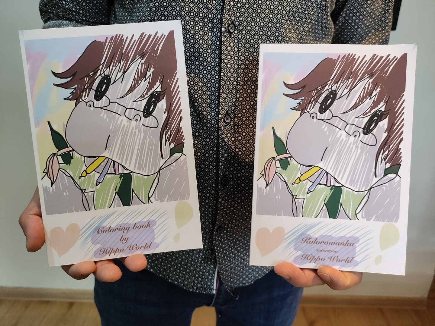 a man holding two books with a drawing of a girl