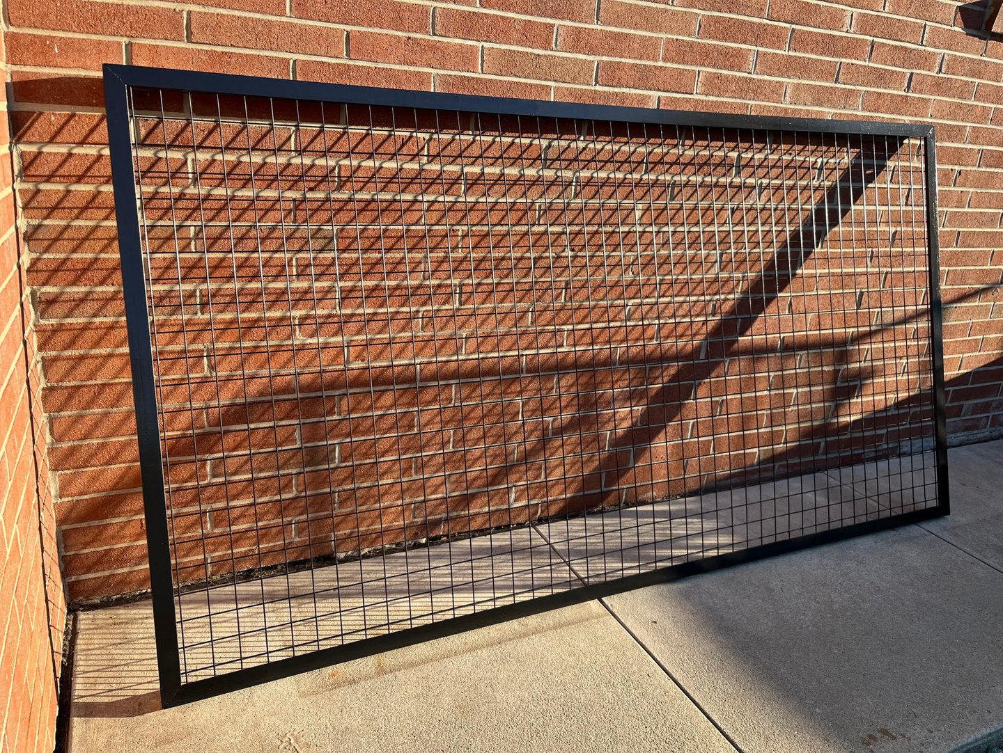 Custom welded wire mesh protective screen leaning against a brick wall