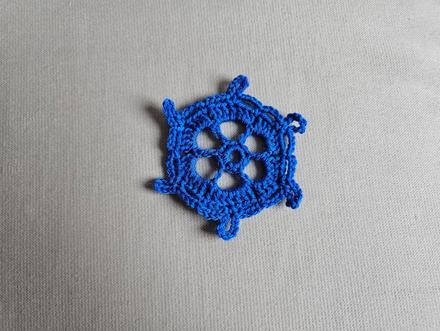 blue crochet snowflake on a light grey background