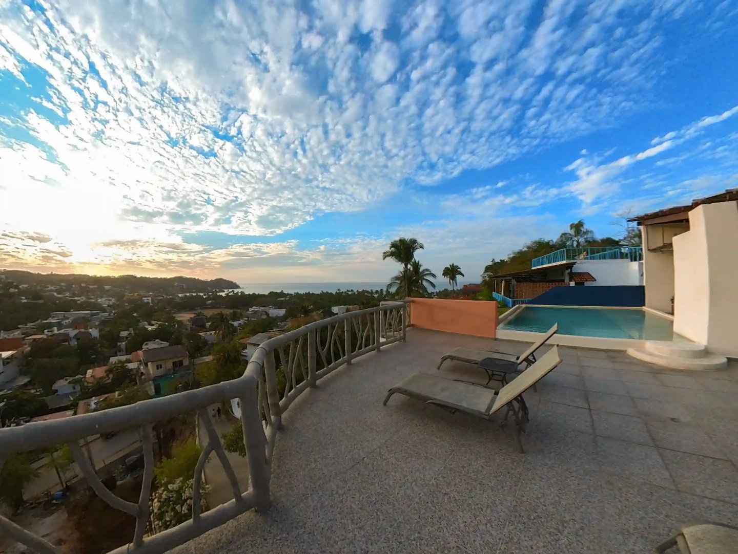 a pool with lounge chairs and a view of the ocean