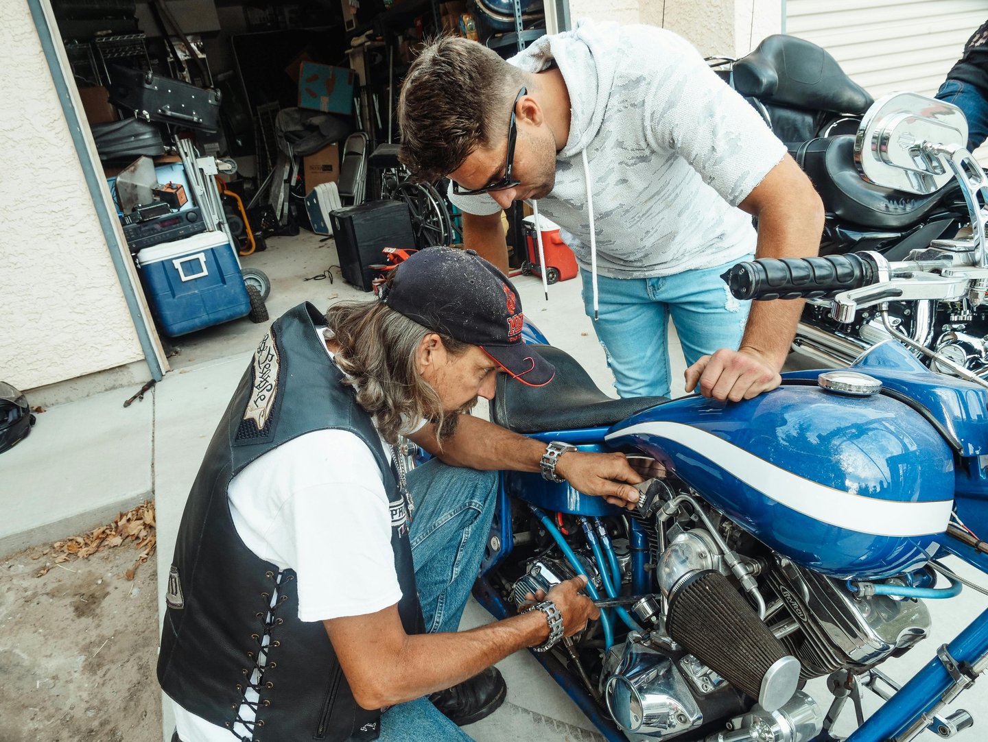 Father performing basic vehicle maintenance demonstration at The Forge workshop
